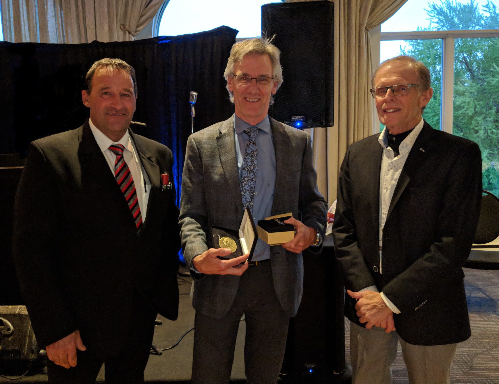 Jean-Pierre Dansereau reçoit le prix Henri-Paul-Gagnon 2019 des mains du premier vice-président et du président de la FPFQ, de MM. Gaétan Boudreault et Pierre-Maurice Gagnon.