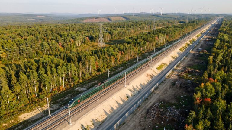 Illustration générée par intelligence artificielle : un train à grande vitesse dans un corridor qui coupe la forêt, une ligne à haute tension et des éoliennes à l’horizon
